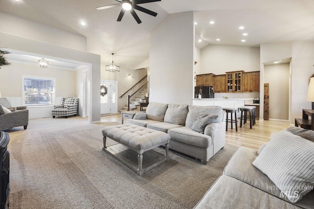 living room featuring high vaulted ceiling, light wood-type flooring, ceiling fan, and ornamental molding