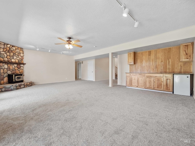 1415 E Lake Crk, Meridian, ID 83642 - unfurnished living room featuring track lighting, a textured ceiling, a ceiling fan, light carpet, and a wood stove