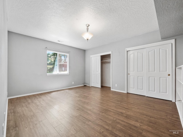 1415 E Lake Crk, Meridian, ID 83642 - unfurnished bedroom featuring two closets, wood finished floors, a textured ceiling, and baseboards