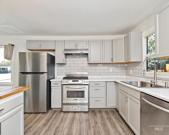 504 E 7th St, Emmett, ID 83617 - kitchen with appliances with stainless steel finishes, a sink, under cabinet range hood, light countertops, and gray cabinetry
