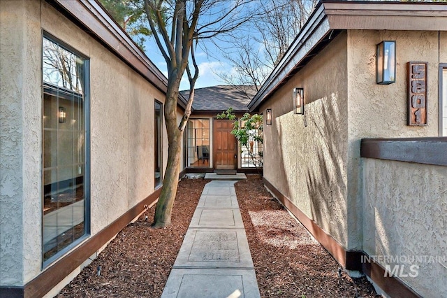 view of side of property featuring stucco siding and roof with shingles