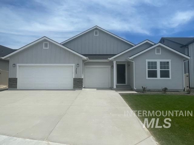 view of front of home featuring a garage, concrete driveway, board and batten siding, and a front yard