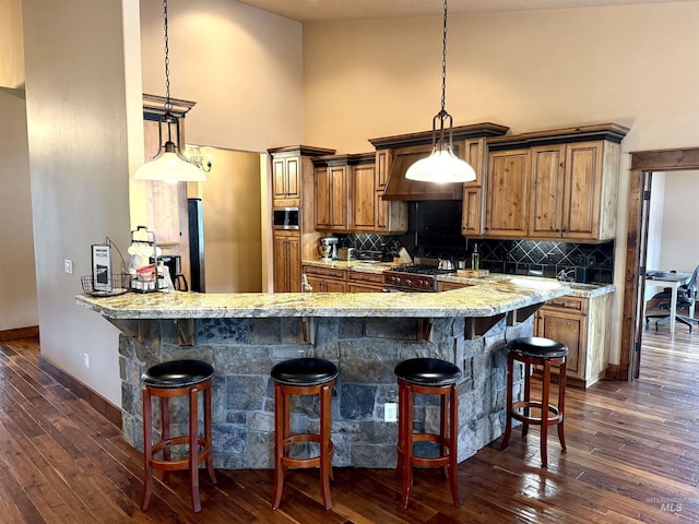 20 Shore Crest Ct, Donnelly, ID 83615 - kitchen featuring a towering ceiling, a breakfast bar area, tasteful backsplash, brown cabinetry, and baseboards