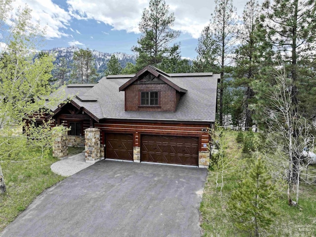 20 Shore Crest Ct, Donnelly, ID 83615 - log-style house featuring driveway, an attached garage, stone siding, a mountain view, and a shingled roof