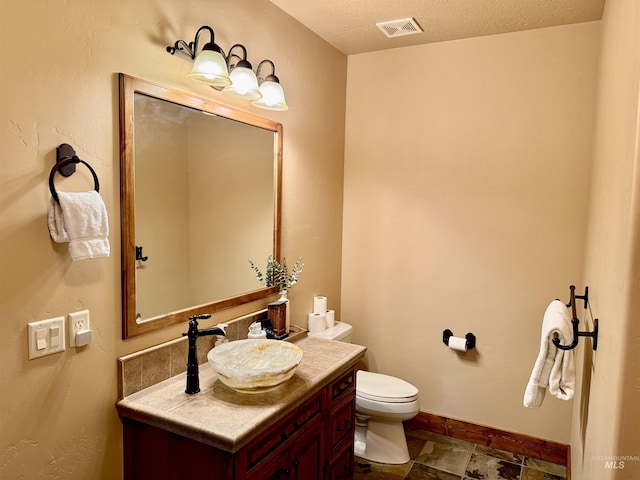 20 Shore Crest Ct, Donnelly, ID 83615 - bathroom featuring vanity, toilet, baseboards, and stone finish flooring