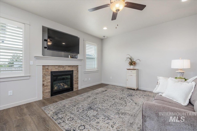 living room with a ceiling fan, wood finished floors, baseboards, a glass covered fireplace, and recessed lighting