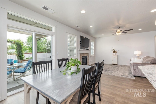 dining area with a glass covered fireplace, recessed lighting, a ceiling fan, and light wood finished floors