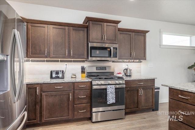 kitchen with stainless steel appliances, tasteful backsplash, light wood-style flooring, and dark brown cabinetry
