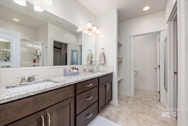 full bath featuring a spacious closet, a shower stall, and double vanity
