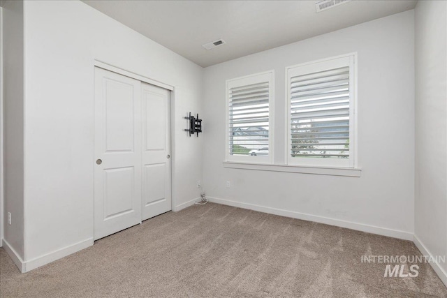 unfurnished bedroom featuring light carpet, baseboards, and a closet