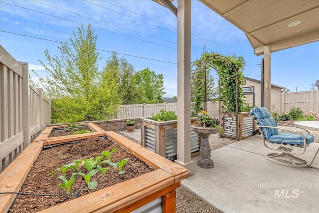 view of patio with a vegetable garden and a fenced backyard