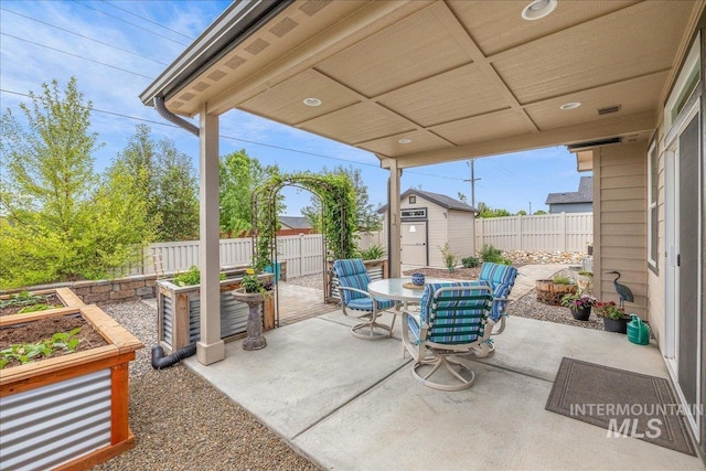 view of patio featuring a storage unit, outdoor dining area, an outbuilding, and a fenced backyard