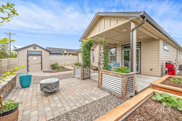 view of patio / terrace featuring a shed, a fenced backyard, an outbuilding, and an outdoor fire pit