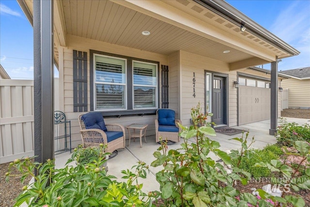 view of patio / terrace featuring concrete driveway, fence, and covered porch