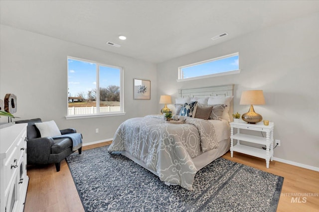 bedroom featuring baseboards, wood finished floors, and visible vents