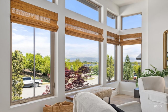 sunroom / solarium with baseboards, a high ceiling, and wood finished floors