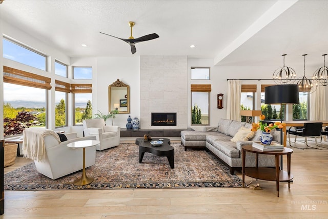living room featuring a fireplace, ceiling fan with notable chandelier, recessed lighting, and wood finished floors