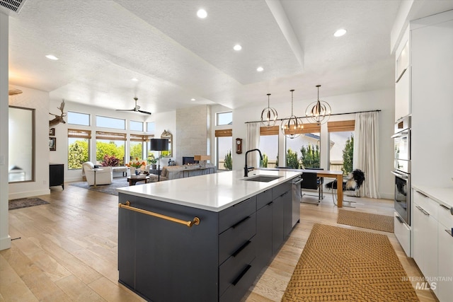 kitchen with an island with sink, a sink, a textured ceiling, and modern cabinets