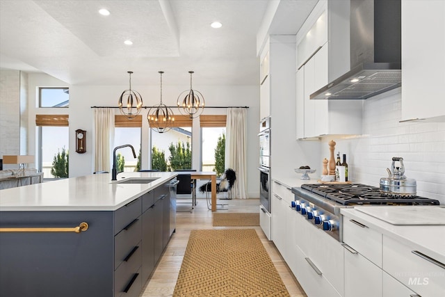 kitchen with stainless steel appliances, a sink, wall chimney exhaust hood, and modern cabinets