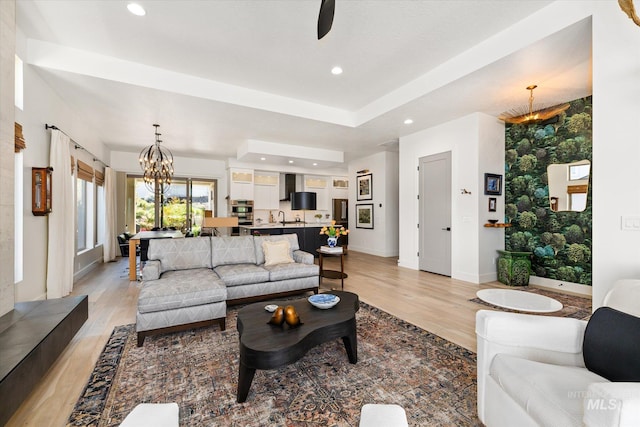 living room with recessed lighting, baseboards, light wood finished floors, and ceiling fan with notable chandelier