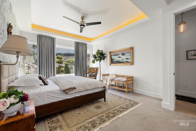 bedroom with baseboards, a ceiling fan, and a tray ceiling