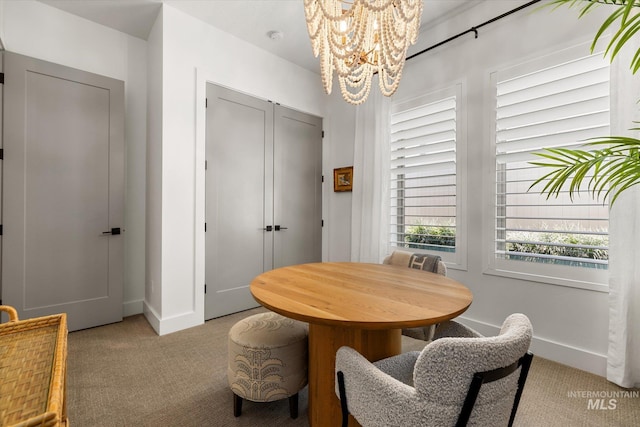 carpeted dining space featuring baseboards and a notable chandelier