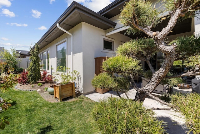 view of side of home with a lawn and stucco siding