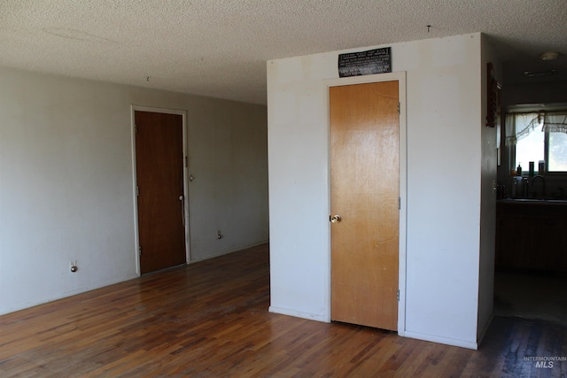 unfurnished bedroom featuring a textured ceiling and dark hardwood / wood-style floors