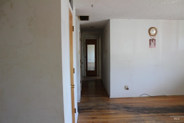 hall with a textured ceiling and dark wood-type flooring