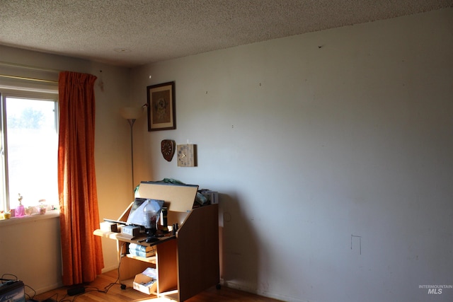 interior space with a textured ceiling and hardwood / wood-style floors