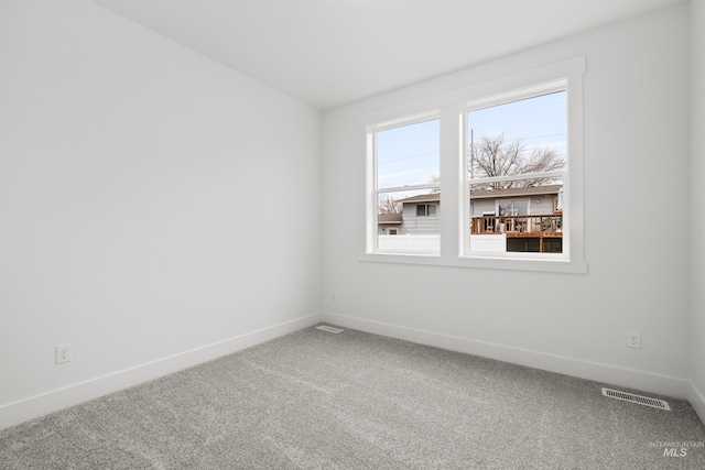 spare room featuring carpet floors, visible vents, and baseboards