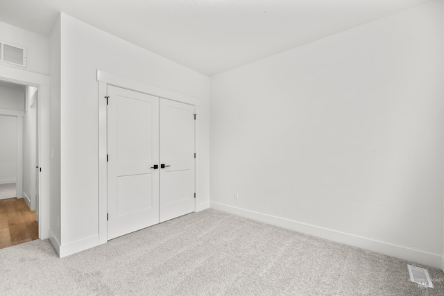 unfurnished bedroom featuring carpet floors, a closet, visible vents, and baseboards