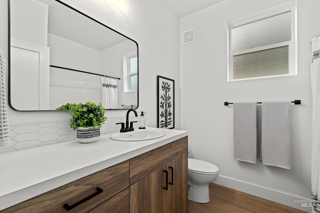 full bath with baseboards, visible vents, toilet, wood finished floors, and vanity