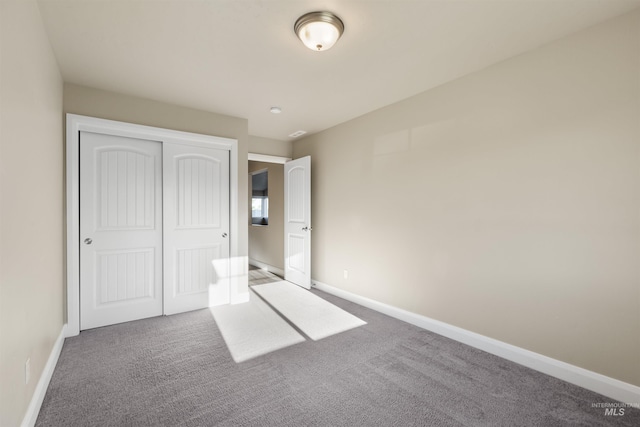 unfurnished bedroom featuring carpet floors, baseboards, and a closet