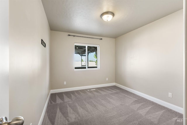 carpeted spare room featuring baseboards