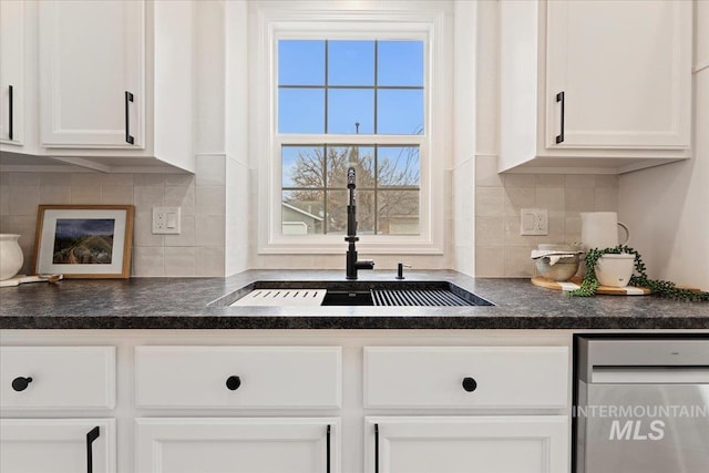 kitchen featuring white cabinetry, dark countertops, and a sink