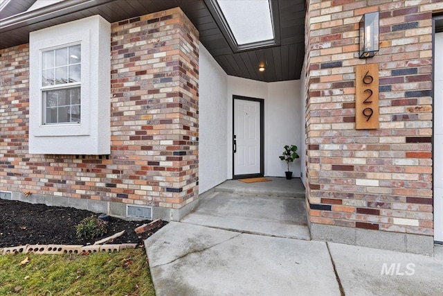 property entrance with brick siding and stucco siding