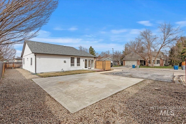 back of property with fence, roof with shingles, and stucco siding