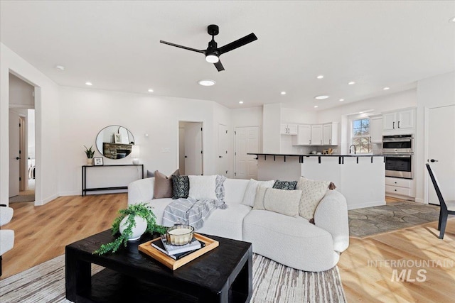 living area featuring recessed lighting, a ceiling fan, and light wood finished floors