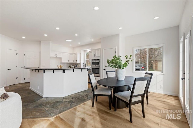 dining room featuring light wood-style flooring, recessed lighting, and baseboards