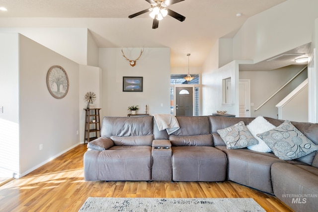 living room featuring ceiling fan, lofted ceiling, and light wood-type flooring