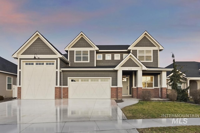 craftsman-style home with concrete driveway, a yard, and brick siding