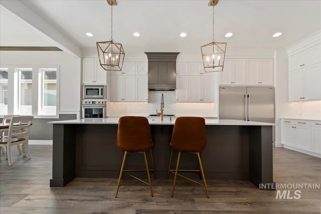 kitchen with built in appliances, light countertops, tasteful backsplash, and a spacious island