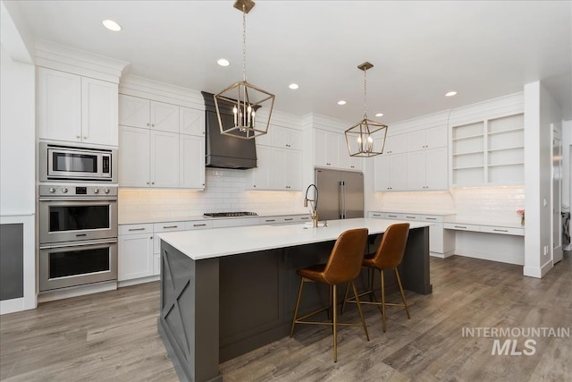 kitchen featuring white cabinets, a kitchen island with sink, open shelves, and built in appliances