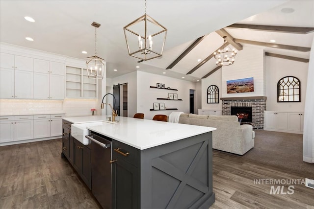 kitchen with a sink, white cabinetry, stainless steel dishwasher, a brick fireplace, and open shelves