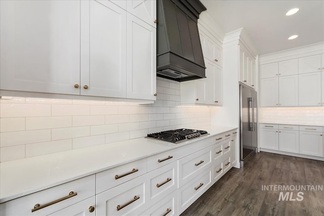 kitchen featuring dark wood finished floors, stainless steel appliances, light countertops, white cabinetry, and premium range hood