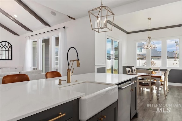 kitchen featuring lofted ceiling with beams, light countertops, a sink, and an inviting chandelier