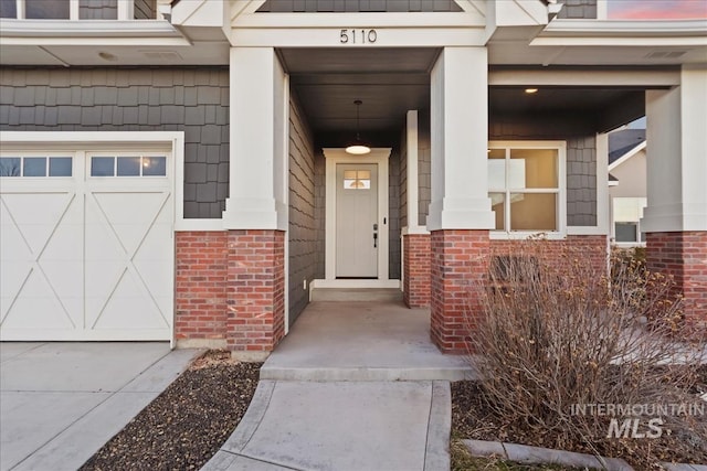 property entrance with a garage, visible vents, and brick siding