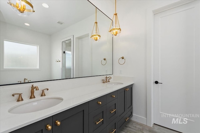 full bathroom with double vanity, visible vents, a sink, and wood finished floors