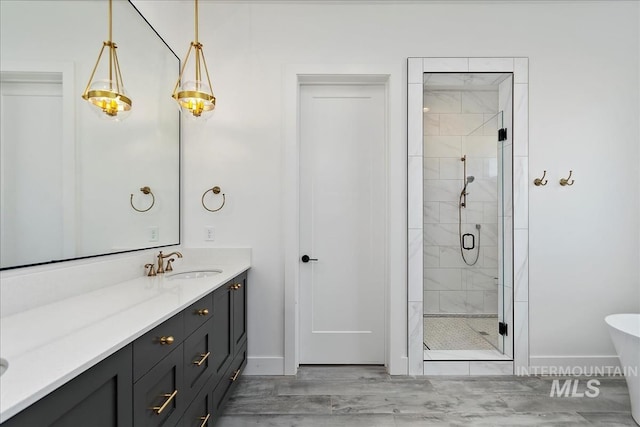 full bathroom featuring a shower stall, baseboards, a freestanding bath, and vanity